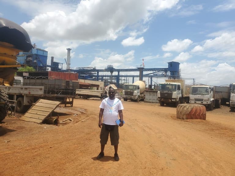 Parc industriel avec camions, engins et convoyeurs sous un ciel nuageux